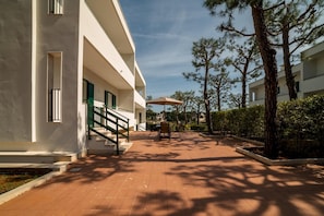 A building with a covered outdoor seating area, a staircase, and a view of the surrounding landscape.
