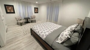 A bedroom with a bed, two chairs, a small table, and a ceiling fan. - The Capitol House (Oklahoma City)