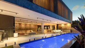 A modern house with a swimming pool, outdoor seating, and a stone wall. - Mana Beach House | Luxury Beach House in Kingscliff (Kingscliff)