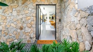 A stone-walled entrance leading to a modern interior with a dining area. - Mana Beach House | Luxury Beach House in Kingscliff (Kingscliff)