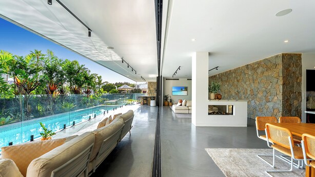 A modern interior with a glass-enclosed pool, a stone wall, and a seating area with a view of the pool. - Mana Beach House | Luxury Beach House in Kingscliff (Kingscliff)