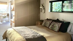 Une chambre à coucher avec un grand lit, une table de chevet, une lampe et une fenêtre donnant sur un paysage verdoyant.