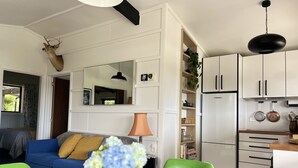 Une cuisine moderne avec des meubles blancs, un luminaire noir suspendu et un réfrigérateur.