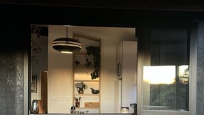 Une cuisine avec un luminaire suspendu, une fenêtre et une vue sur l’extérieur.