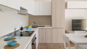 Une cuisine moderne avec des meubles blancs, une cuisinière noire et un évier.