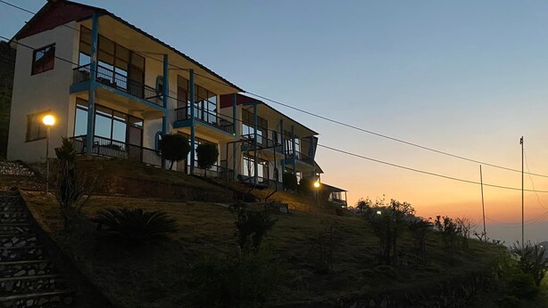 A multi-story building with balconies, a stone staircase, and a sunset in the background. - Sindhuligadhi Mountain Resort (Ratanchura)
