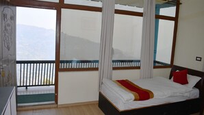 A bedroom with a bed, a view of mountains through large windows, and a balcony with a railing. - Sindhuligadhi Mountain Resort (Ratanchura)