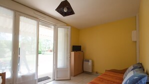 A room with a bed, a television, a wardrobe, and a sliding glass door leading to an outdoor area. - Tasteful cottage in Sauze-Vaussais with terrace (SAUZE-VAUSSAIS)