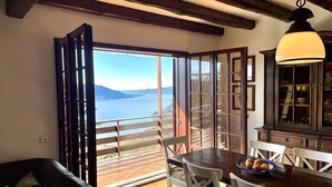 Une pièce avec un plafond en bois, une table à manger avec des chaises, un buffet en bois et une vue sur un lac, visible à travers une porte coulissante.