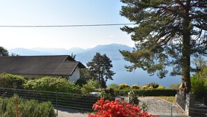 Une maison avec un toit en tuiles, donnant sur un lac et des montagnes.