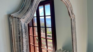 Une pièce dotée d’un grand miroir décoratif qui reflète la vue d’un balcon orné d’une balustrade en bois et d’un ciel dégagé.
