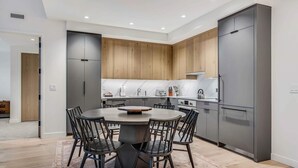 A modern kitchen with a central island, wooden cabinets, and built-in appliances. - Electric Pass Lodge 604 (Snowmass)