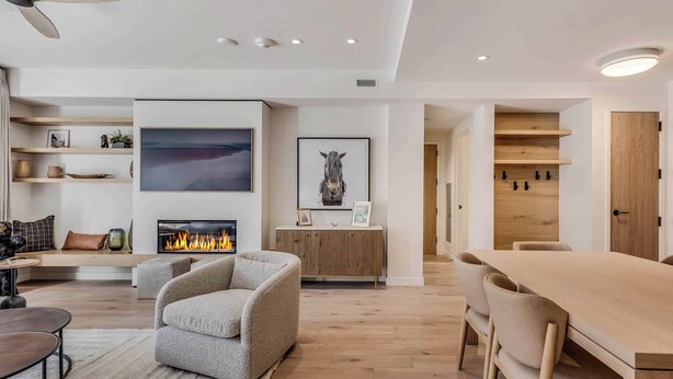 Un salon moderne avec une cheminée, un canapé, une table à manger et un ventilateur de plafond.