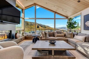 Una sala de estar moderna con un ventanal grande, una chimenea y una zona de estar confortable.