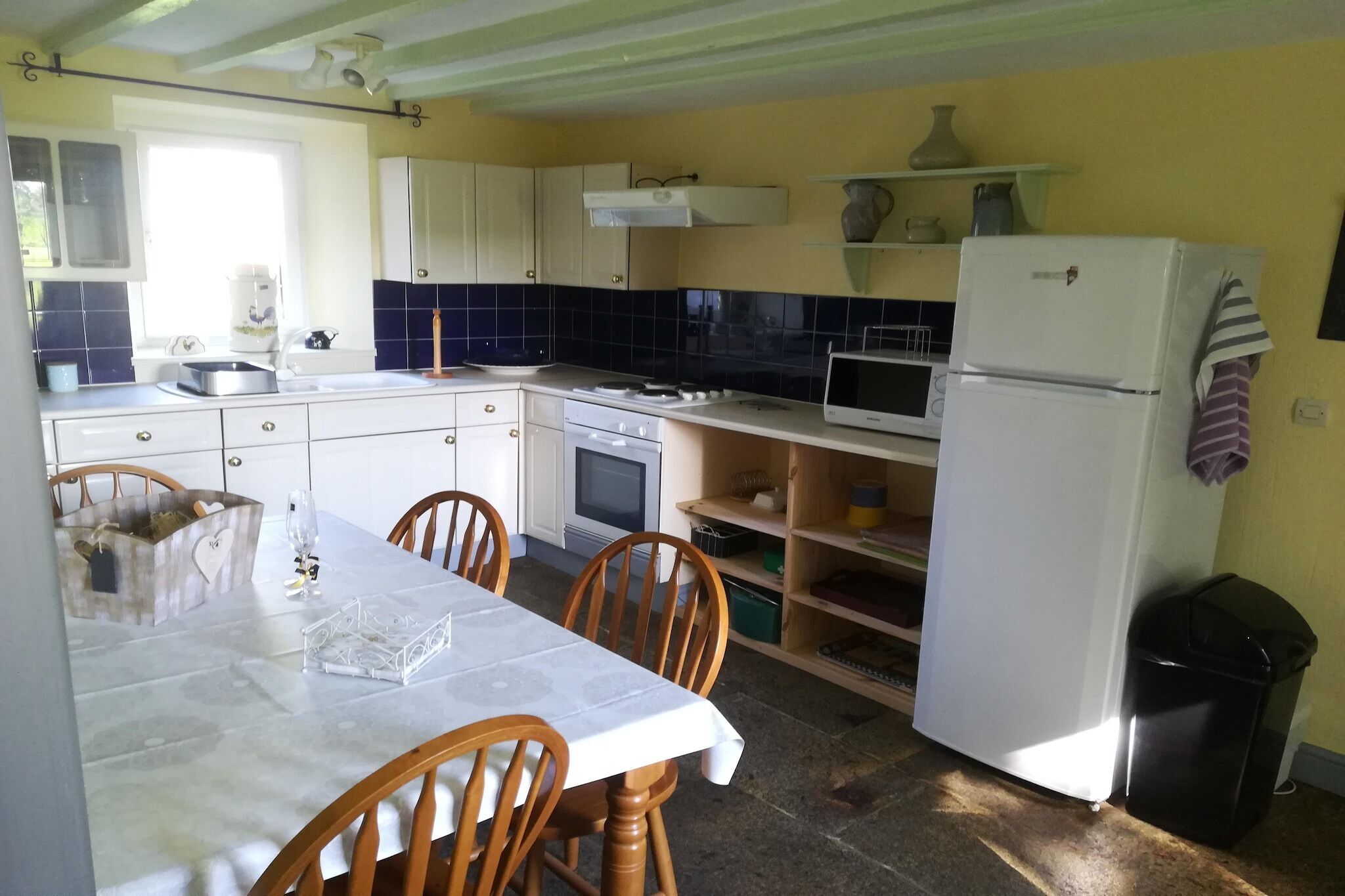 A compact kitchen with white cabinets, a dining table, and chairs.