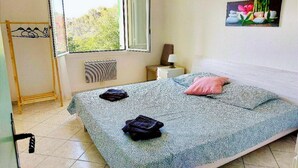 Une chambre à coucher comprenant un lit, une fenêtre, un radiateur, une table de chevet avec une lampe et un tableau accroché au mur.