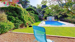 Un jardin avec une piscine, une construction en pierre et une chaise.