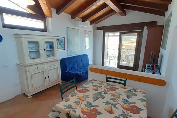 A room with a bed, a dining table, a blue sofa, and a white cabinet.