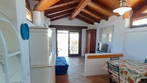 Una cocina compacta con refrigerador, una mesa de comedor con mantel estampado de frutas y techo de madera.