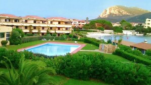 Un hotel con piscina rodeado de exuberante vegetación y una montaña al fondo.