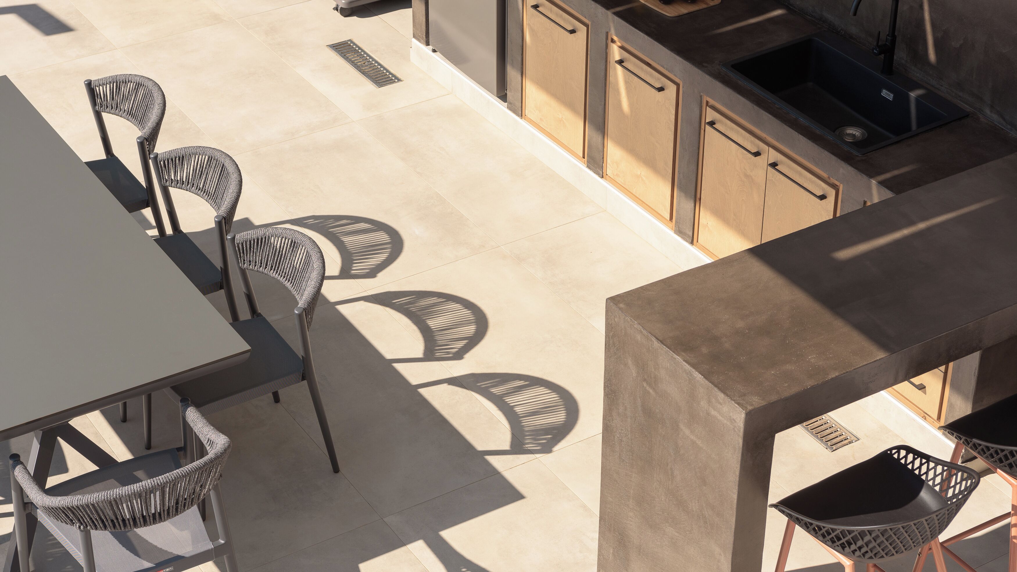 Un espace extérieur aménagé en patio, avec une table et des chaises, un coin cuisine doté de placards et d’un évier, ainsi qu’un drain.