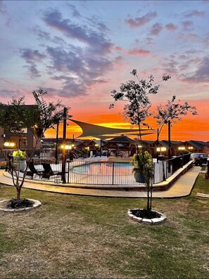 A pool area with a sunset view, surrounded by buildings and trees. - Belas Resort (Willis)