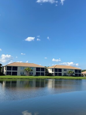 Een gebouw met twee verdiepingen, een pannendak, grote ramen en een weerspiegeling in het water ervoor.