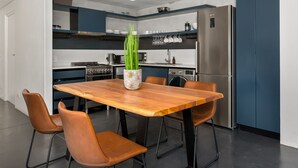A modern kitchen with a wooden dining table, brown chairs, and a potted plant. - FortyOnL 810 (Cape Town)