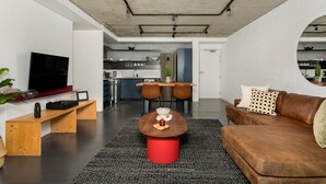 A modern living room with a wooden coffee table, a brown leather sofa, and a TV mounted on the wall. - FortyOnL 810 (Cape Town)
