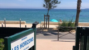 Schild für 'LES HORIZONS', Privatgrundstück, Meerblick und eine Person sitzt unter einem blauen Sonnenschirm.