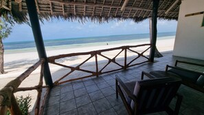 A covered outdoor seating area with a view of the beach.