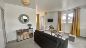 Un salon moderne comprenant un canapé, une table basse, un téléviseur et un coin repas avec une chaise et une table.