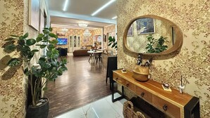 Ein großzügiges Wohnzimmer mit Holzboden, einem großen runden Spiegel und einer Essecke mit Tisch und Stühlen.