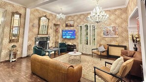 Ein geräumiges Wohnzimmer mit Kamin, bequemen Sitzgelegenheiten, einem Fernseher und Dekorationselementen.