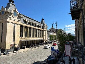 Historiallinen rakennus, jossa on suuri julkisivu, kellotorni ja edessä oleva katu, jolla on jalankulkijoita ja parkkeerattuja autoja.