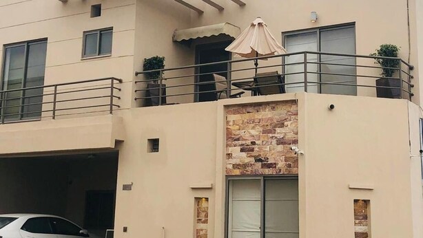 Um edifício moderno de dois andares com varanda, área de estar coberta ao ar livre e garagem.