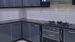 Une cuisine avec des meubles de couleur noire, un pare-feu en carrelage et une cuisinière à gaz.