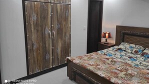 Um quarto com uma cama, um guarda-roupa, uma mesa de cabeceira e um aparelho de ar condicionado.