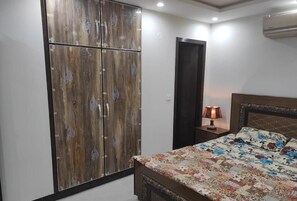 A bedroom with a bed, a wardrobe, a nightstand, and an air conditioning unit. - Beautiful home at the heart of Islamabad (islamabad)