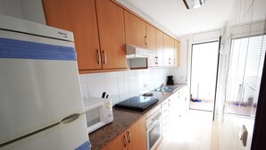 Una cocina moderna con armarios de madera, un refrigerador de acero inoxidable, un microondas y una estufa a gas.