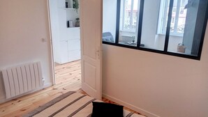 Un corridoio con un tappeto a righe, un termosifone e una porta che dà su un balcone con vista all'esterno.