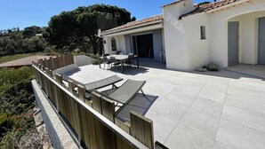 Un patio con una mesa y sillas, cerca de una valla de madera y un edificio con tejado de tejas.