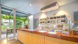 Un espace bar avec un comptoir en bois, des bouteilles de vin, des verres et un tableau affichant le menu.