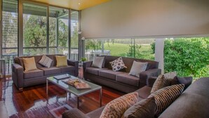 Un salon moderne avec deux canapés, une table basse et de grandes fenêtres donnant sur un paysage verdoyant.