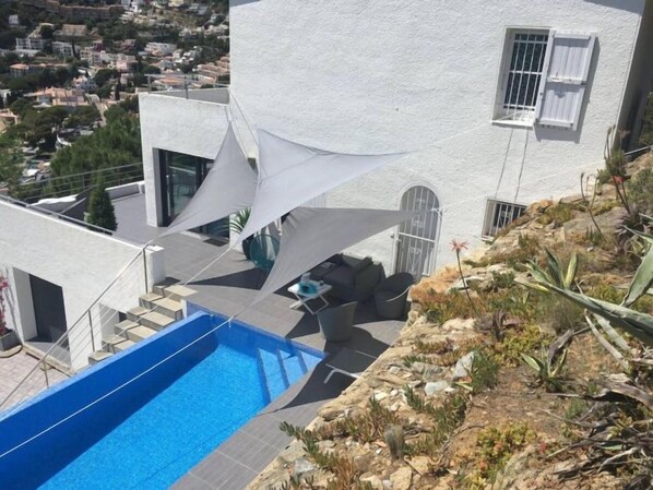 A modern house with a swimming pool, white walls, and a view of the surrounding area.