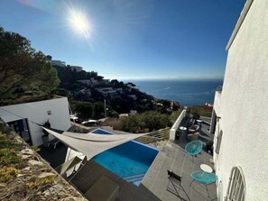 A rooftop pool with a view of the ocean and a cityscape in the background.