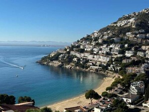 A coastal town with buildings on a hillside overlooking a beach. - Villa Eden Roc Av 22 (Rosas / Roses)