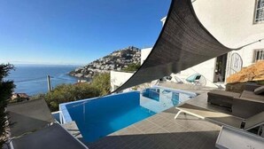 A swimming pool with a view of the sea and a hillside town.