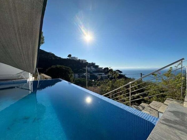 An infinity pool with a clear view of the ocean and a hillside in the background. - Villa Eden Roc Av 22 (Rosas / Roses)