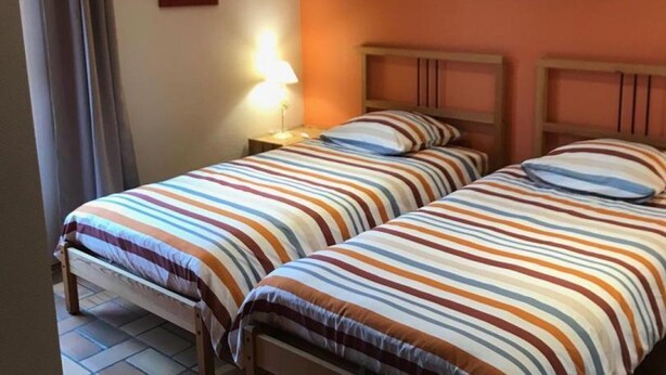 A room with two beds, a nightstand with a lamp, and two wall-mounted paintings. - Single-storey house, pets welcome - 6 guests (Caulaincourt)